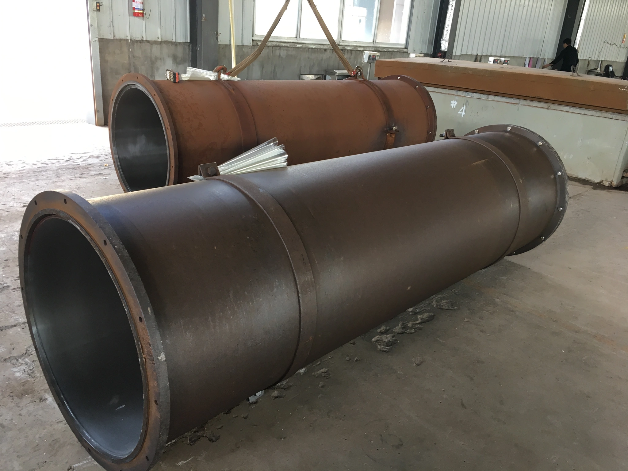 Large cylindrical metal tooling or moulds in the workshop